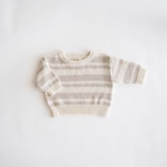 This Organic Knit Sweater is perfect for cooler sweater weather days. This sweater offers a lighter weave for a delicate touch, making it an ideal choice for the milder days of fall. Elegantly crafted in a soft ecru, and also available in ecru with oat milk stripes, it captures the essence of the harvest season with a classic flair. Lovingly made from 100% organic cotton, this sweater helps ensure an environmentally friendly footprint and a gentle caress against your baby’s skin. Sock Booties, Weather Day, Harvest Season, Skirt Jumpsuit, Swim Sets, The Harvest, Oat Milk, Resort Collection, Knit Sweatshirt