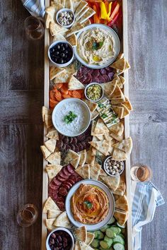 a wooden tray filled with different types of food and dips on top of it