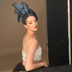 a woman sitting on the floor with her eyes closed wearing a blue bow headband