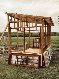 a wooden structure sitting in the middle of a grass covered field next to a ladder