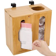 a person is opening the door to a wooden box that has tissue in it and there are plastic bags inside