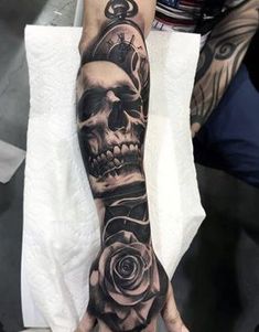 a hand with a skull and rose tattoo on it