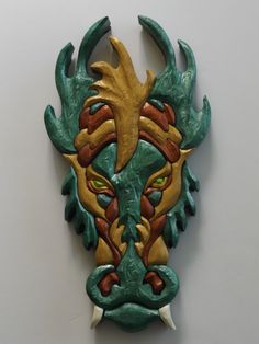 a green and yellow mask with horns on it's face is hanging from the wall