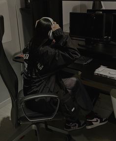 a person sitting at a desk with headphones in their ears, listening to music