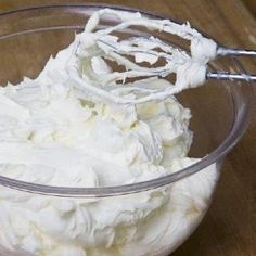 a bowl filled with whipped cream on top of a wooden table