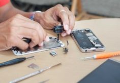 a person working on an iphone with tools around him and the phone being removed from its housing