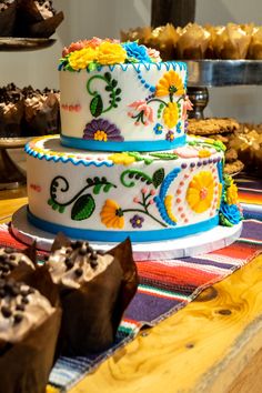 a multi layer cake sitting on top of a table next to cupcakes and muffins