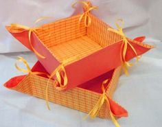 two orange boxes sitting on top of each other with yellow ribbons around the bottom and sides