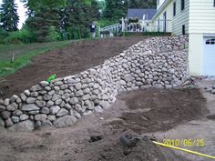 a pile of rocks sitting on top of a dirt field next to a house with a yellow measuring tape