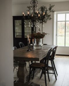 a dining room table with chairs and a vase filled with flowers on top of it