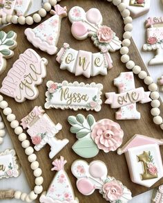 some decorated cookies are laying on a wooden board with white and pink decorations around them