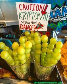 two vases filled with green grapes sitting on top of a counter