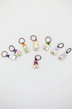 six keychains with different designs on them sitting in the middle of a white surface