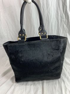 "Measurements are 14\" top wide, 10\"5 high, 5\"8 deep with two 48\" straps each side to side with a 8\" drop. On the interior there is one main compartment, unlined leather, back zipper pocket and a top magnetic closure. Bag is made of calf hair with black leather trim, gold tone hardware and chunky handles. Please note bag is not new and there are scuffs with some balding and bag is great for daily use and will last you for years to come. I WANT TO STRESS THAT THIS ITEM IS VINTAGE WHICH MEANS Black Shoulder Bag With Leather Lining And Double Handle, Chic Leather-backed Tote Satchel, Chic Satchel With Leather Backing And Tote Shape, Medium Black Shoulder Bag With Handles, Black Calf Hair Shoulder Bag For Everyday Use, Black Medium Bags With Handles, Large Chic Black Satchel, Everyday Calf Hair Shoulder Bag With Leather Handles, Everyday Shoulder Bag With Leather Handles And Calf Hair