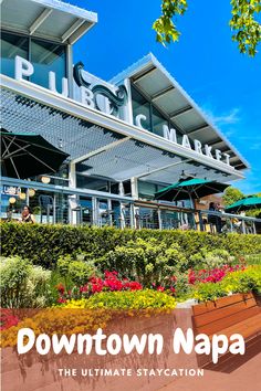 The outside of Oxbow Public Market in Downtown Napa which is a popular marketplace with a variety of restaurants to choose from. There are lots of flowers and benches lined up outside the marketplace for people to sit and enjoy their food Oxbow Market Napa, Oxbow Public Market Napa, Downtown Napa Valley, Napa Valley Itinerary, Birthday Getaway, Downtown Napa, Birthday 22, Napa Trip, Cali Trip