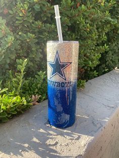 a drink cup with a straw in it sitting on a ledge next to some bushes