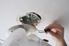 a person is working on a ceiling fan with a light switch in the middle of it