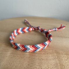 a red, white and blue braided bracelet sitting on top of a wooden table