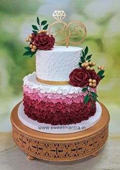 a three tiered cake decorated with red flowers and gold trimmings on a table