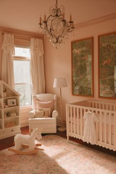 a baby's room with a crib, rocking horse and chandelier