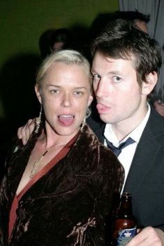 a man and woman are posing for a photo with a beer in their hand at a party