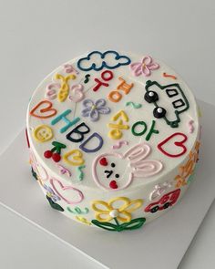 a birthday cake decorated with colorful letters and numbers on top of a white sheet paper