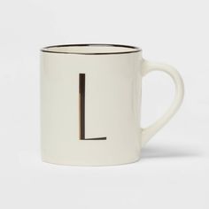 a white and black coffee mug with the letter l on it's front side