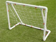 a soccer goal on the grass with red balls in it's back end and white posts