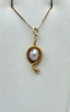 This is a rare antique Victorian Snake Pendant Necklace depicting a snake or serpent wrapped around an egg or globe. The snake is beautifully created in 14 Karat yellow gold. The egg or globe is a gorgeous Baroque Pearl of a stunning silver color. The snake pendant dates to circa 1850-1900. It is extremely rare to find these early snake jewels and we are so excited when we do. The combination of the stunning rendering of the golden snake with the silvery white hues of the natural baroque pearl create a wonderful antique jewel that is full of both drama and whimsy and the power and beauty of the natural world. And snake jewelry is all the rage today. In the Victorian era the snake was the symbol of eternal love. It has come to symbolize sexuality, rebirth and wisdom. The snake pendant is 1 18th Century Jewelry Necklaces, Dagger Jewelry, Antique Jewelry Rare, 16th Century Jewelry, Scarab Jewelry, 18th Century Jewelry, Rep Era, Antique Jewelry Victorian, Serpent Jewelry