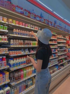 a woman wearing a face mask is shopping in a grocery store with her hand on the shelf