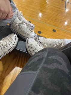 two people sitting on top of a skateboard in front of a person with their feet up