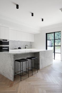 an image of a kitchen with marble counter tops and stools in the foreground