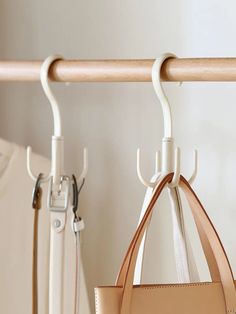 two purses are hanging on the clothes rack in front of a white coat hanger