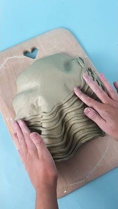 two hands are working on a clay sculpture that looks like a woman's head