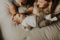 a man and woman holding a baby on top of a bed