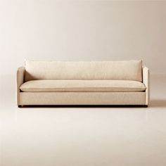 a white couch sitting on top of a floor next to a beige wall with a wooden frame