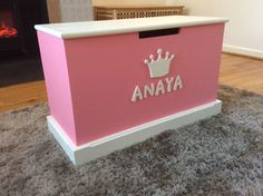 a pink toy chest sitting on top of a rug in front of a fire place