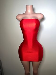 a mannequin wearing a red dress in front of a white wall