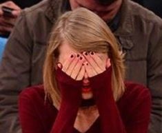 a woman covering her face with hands while sitting in front of a man at a basketball game