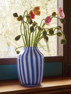 a blue and white striped vase with flowers in it