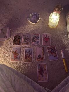 the tarot cards are laid out on the floor next to a candle and some pens