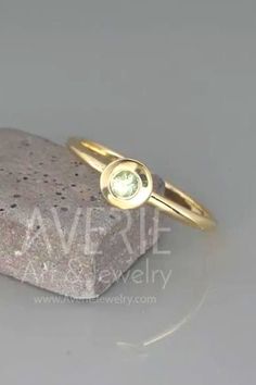 a gold ring with a green stone in the middle on top of a white rock