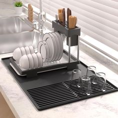 a dish rack with plates and glasses on top of a kitchen counter next to a sink