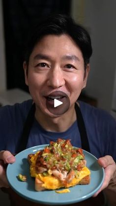 a man holding a plate with an omelet on it in front of his mouth