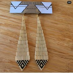 the earrings are made from bamboo and beaded with black, white and gold beads