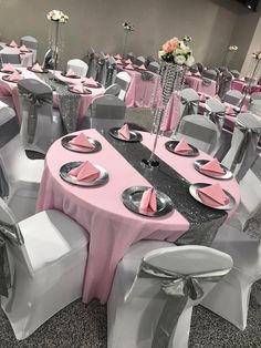 tables and chairs are set up for a formal function with pink napkins on them