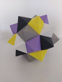 an origami sculpture is displayed on a white surface with purple, yellow and black colors