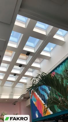 the skylights are shining brightly in this office building's atrium area, with palm trees and paintings on the walls