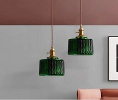 two green glass pendant lights hanging from the ceiling in a living room with pink chairs