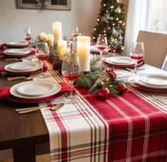 a ghingam red table runner with festive centerpiece, candles and a beautifully set table next to a christmas tree decorated with string lights. Centerpiece Candles, Red Christmas Decorations, Christmas Dining Room Table, Red Table Runner, Christmas Tree Decorated, Red Christmas Decor, Round Kitchen Table, Festive Centerpieces, Christmas Dining Room